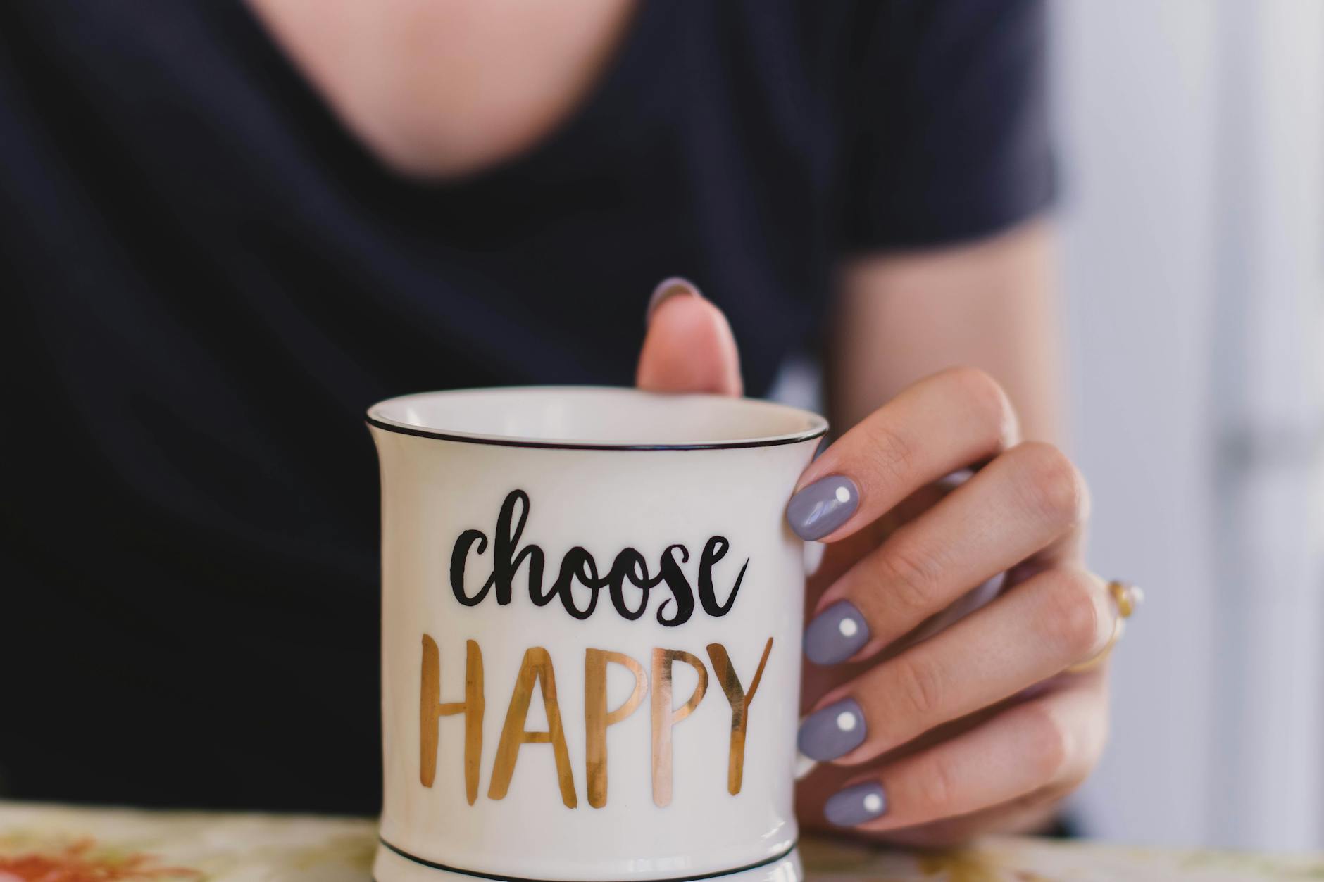 selective focus photography of person touch the white ceramic mug with choose happy graphic